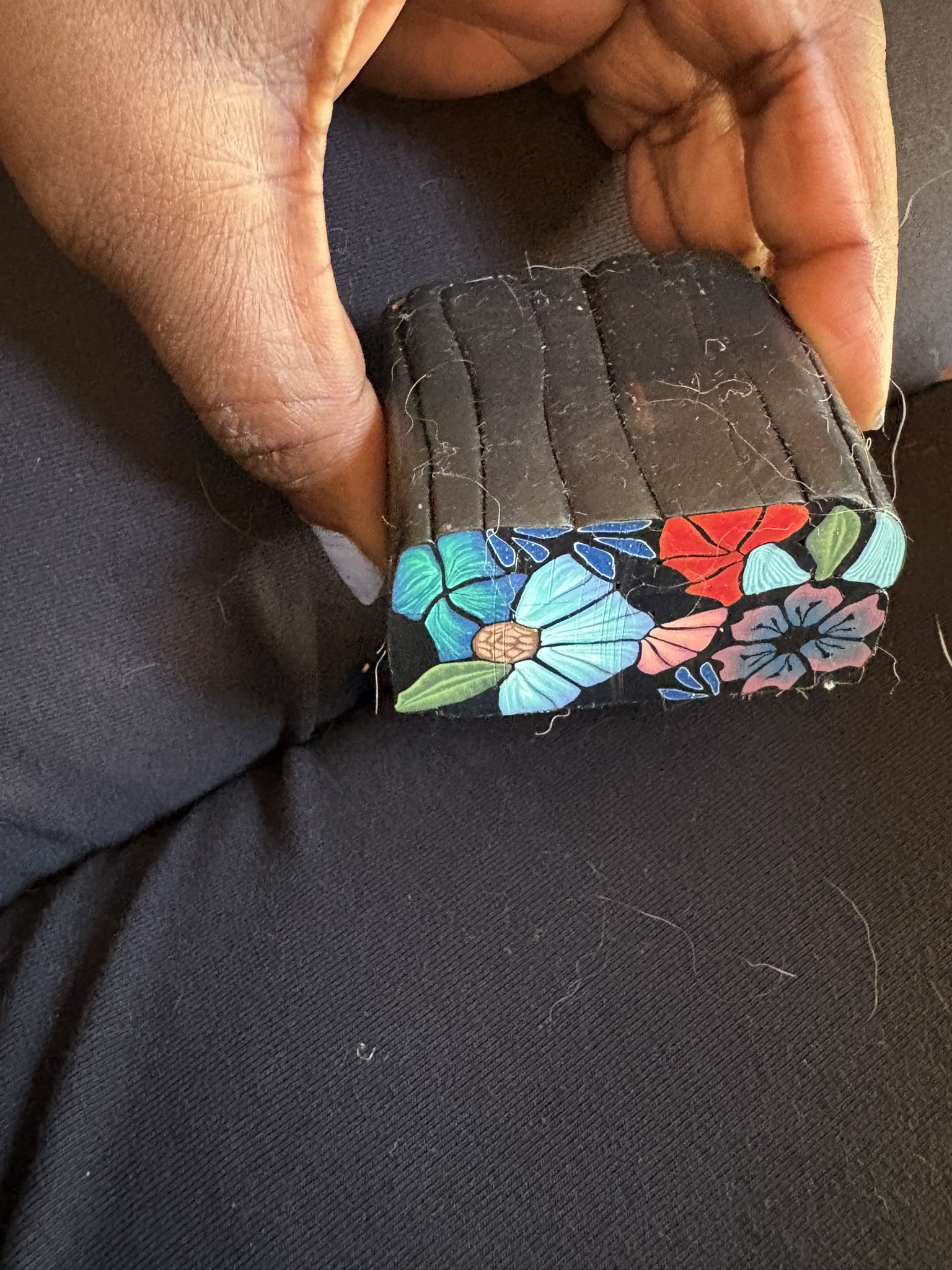 Black floral millefiori cane held in the hand